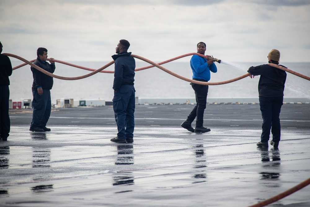 USS Tripoli Sailors wash the flight deck