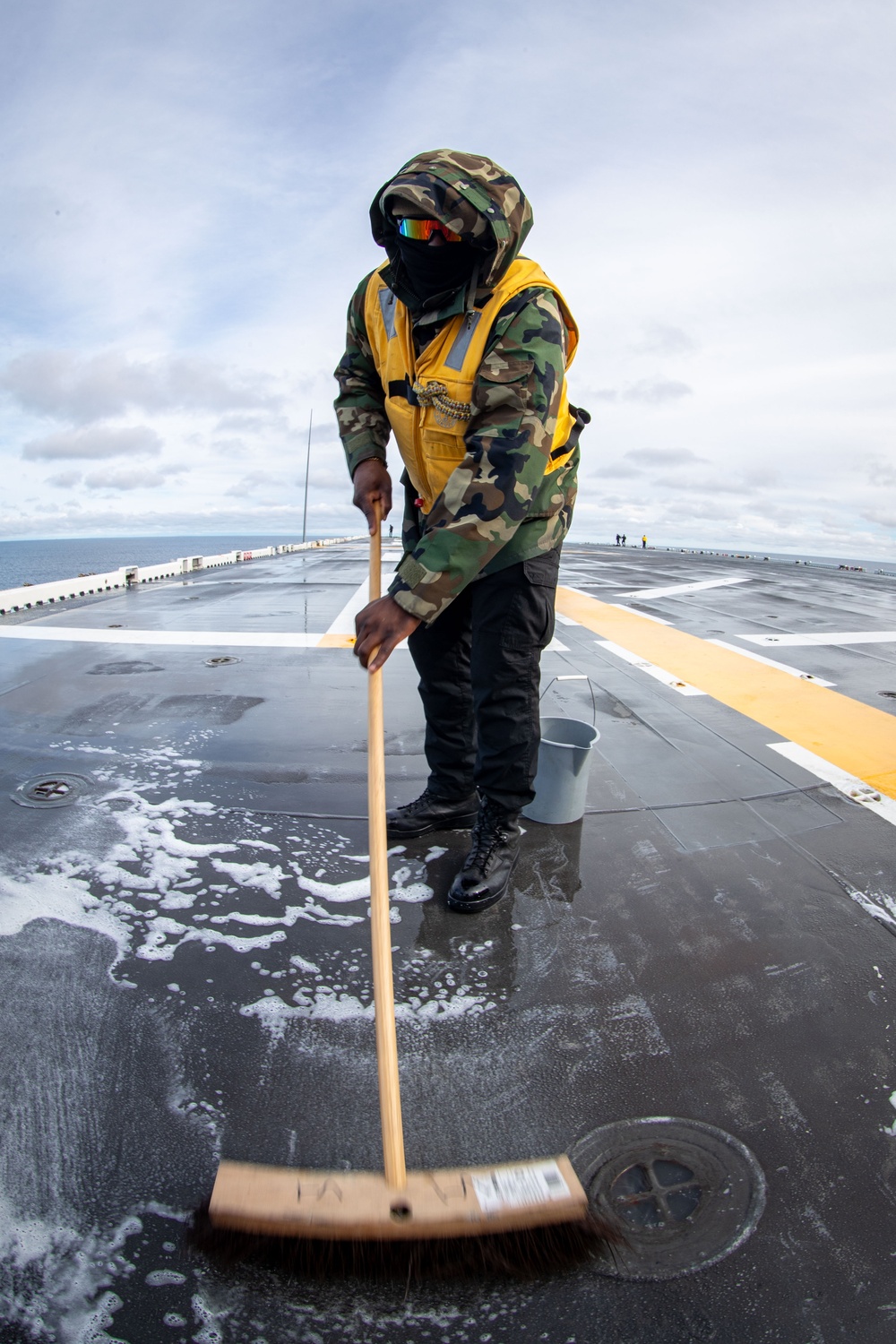 USS Tripoli Sailors wash the flight deck