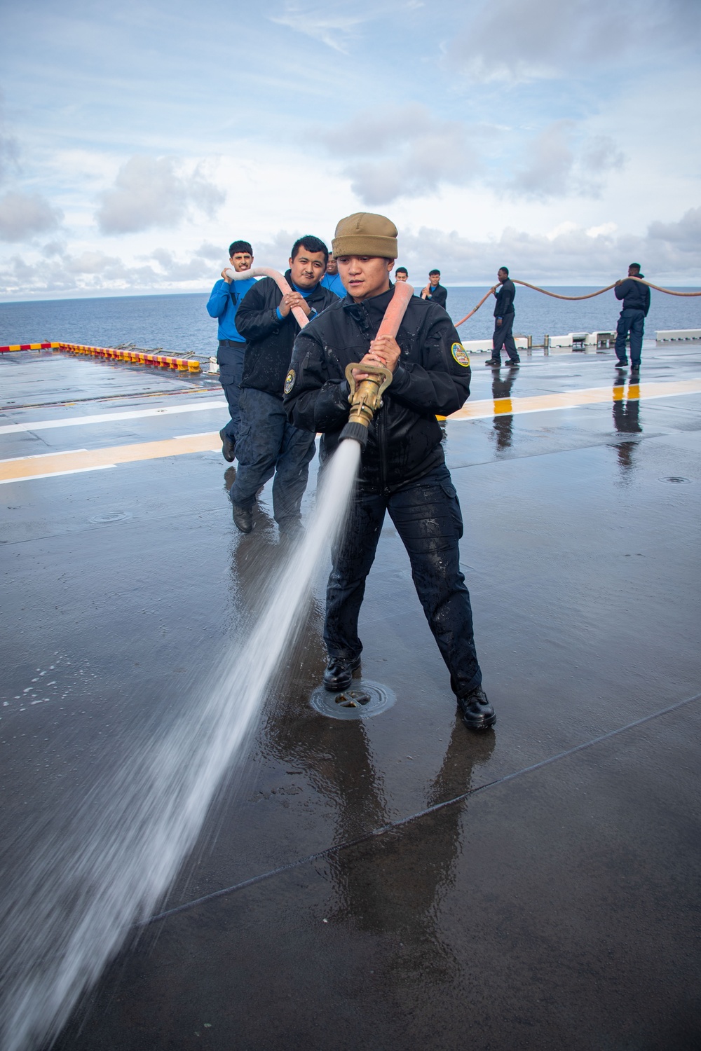 USS Tripoli Sailors wash the flight deck