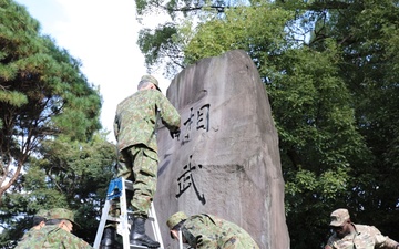 765th Transportation (Terminal) Bn. Soldiers, Japan Ground Self-Defense Force members work together to beautify historical stone monument on Camp Zama