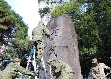765th Transportation (Terminal) Bn. Soldiers, Japan Ground Self-Defense Force members work together to beautify historical stone monument on Camp Zama