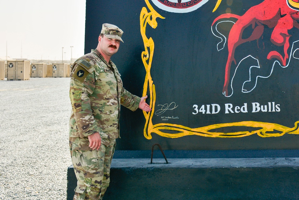 Soldier paints concrete barrier.