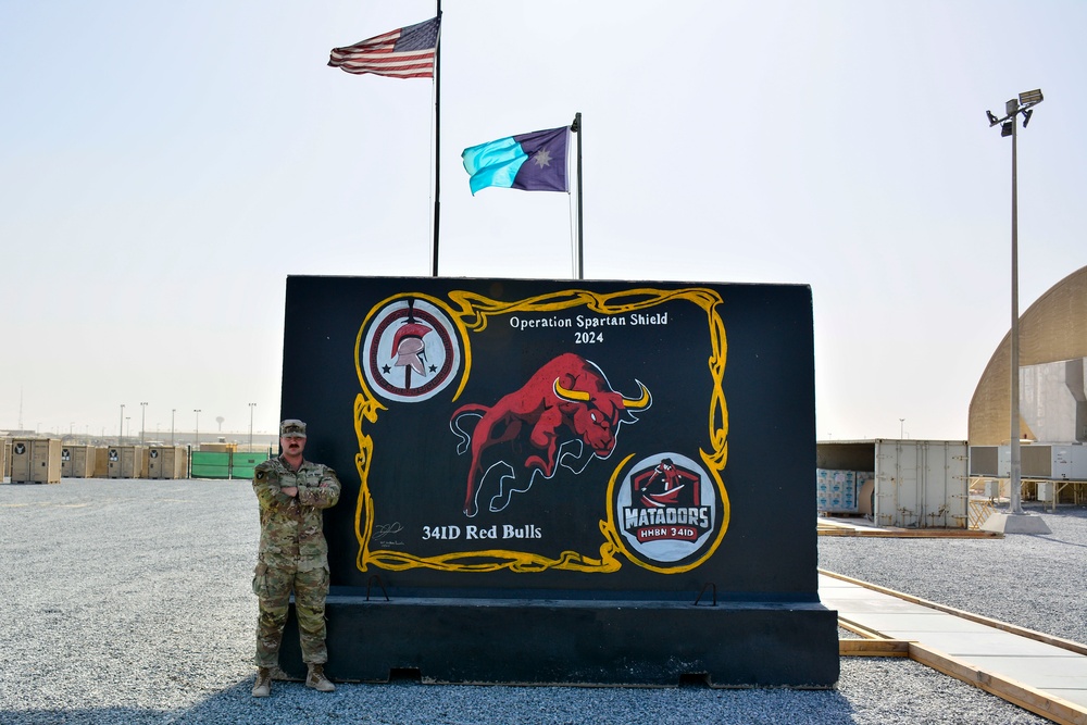 Soldier paints concrete barrier.