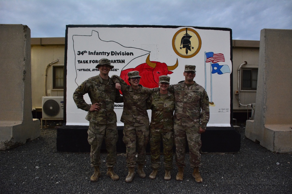 Soldiers paint concrete barrier.