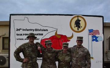 Soldiers paint concrete barrier.