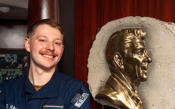 USS Ronald Reagan (CVN 76) Sailor poses with Ronald Reagan plaque