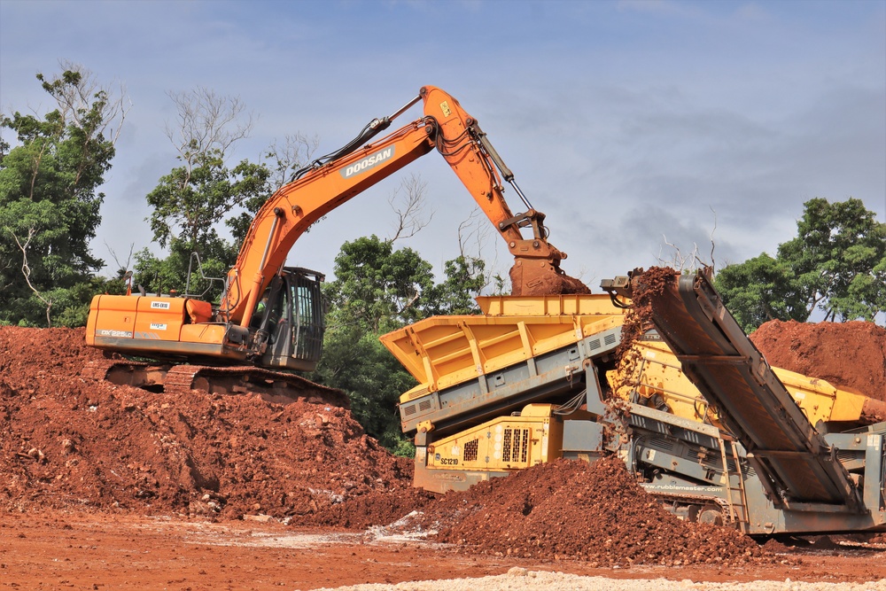 An excavator and materials screener work in tandem to sort soils on an active construction site