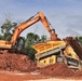 An excavator and materials screener work in tandem to sort soils on an active construction site