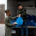 A volunteer hands a gift bag to a Marine at the Holidays in the Barracks event