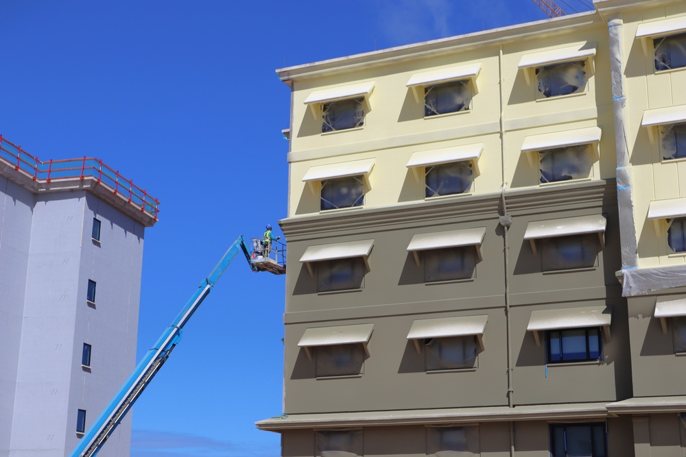 A construction worker adds finishing touches to the facade of a Bachelor Enlisted Quarters on Marine Corps Base Camp Blaz