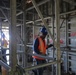 Construction workers navigate scaffolding in a hallway of Marine living quarters under construction