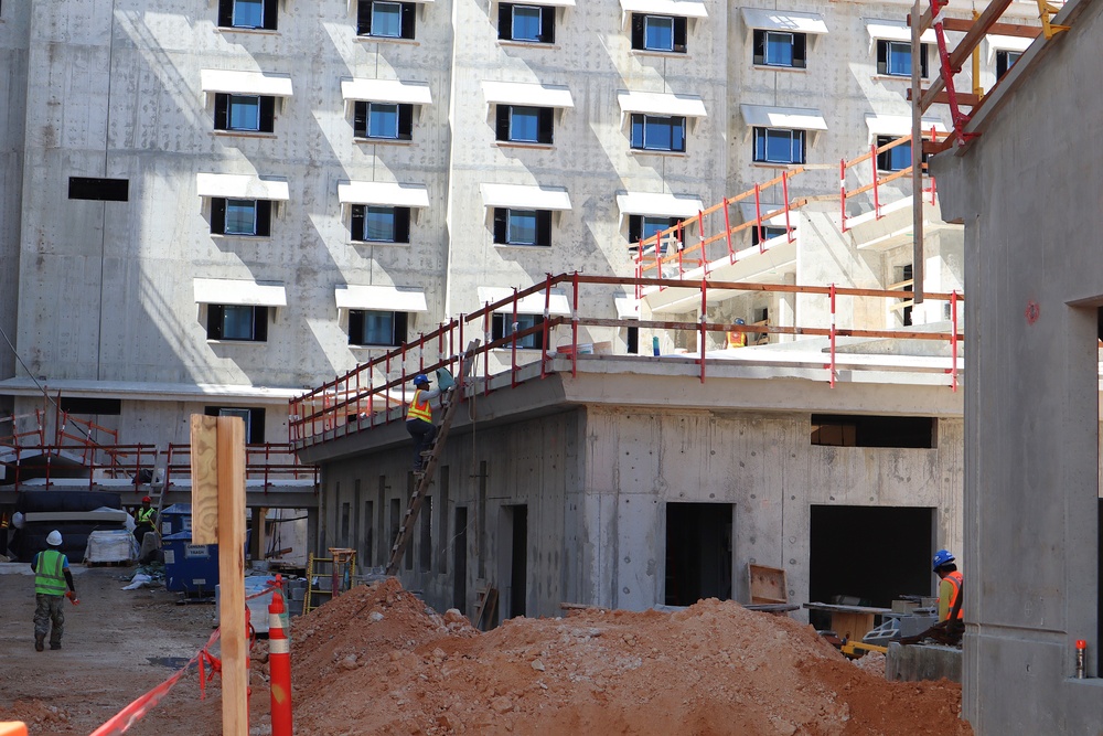 Construction workers scale the walls of a central community facility in a living quarters complex under construction on Marine Corps Base Camp Blaz