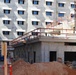 Construction workers scale the walls of a central community facility in a living quarters complex under construction on Marine Corps Base Camp Blaz