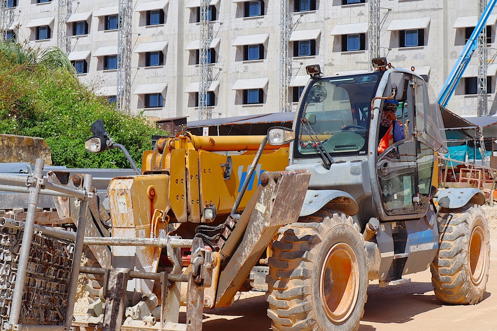 A forklift moves construction equipment during the construction of Bachelor Enlisted Quarters on Marine Corps Base Camp Blaz