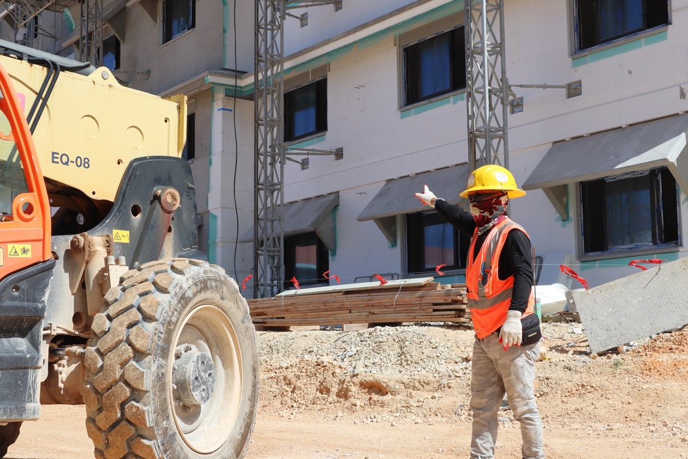 A spotter directs heavy equipment during the construction of Marine Corps Base Camp Blaz