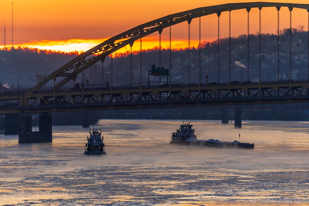 Sunfire and Ice: Towboats navigate through frozen rivers during Pittsburgh sunrise