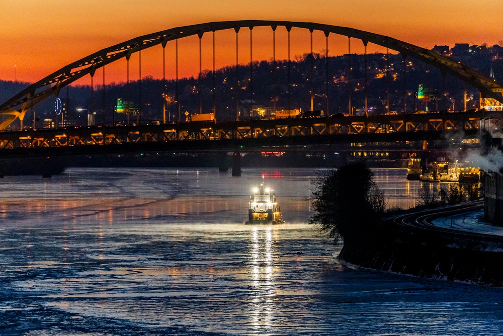 Sunfire and Ice: Towboats navigate through frozen rivers during Pittsburgh sunrise