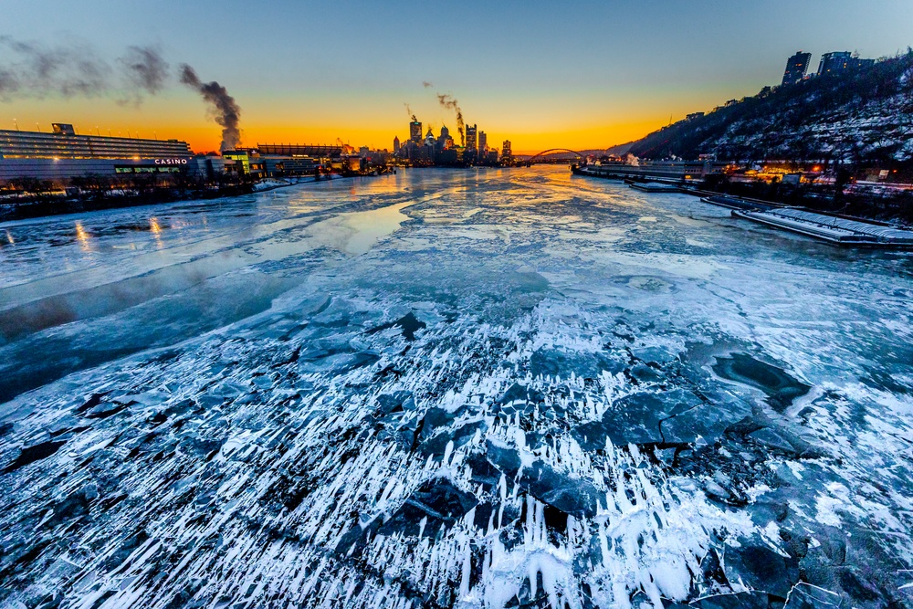 Sunfire and Ice: Towboats navigate through frozen rivers during Pittsburgh sunrise