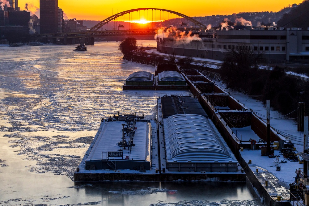 Sunfire and Ice: Towboats navigate through frozen rivers during Pittsburgh sunrise