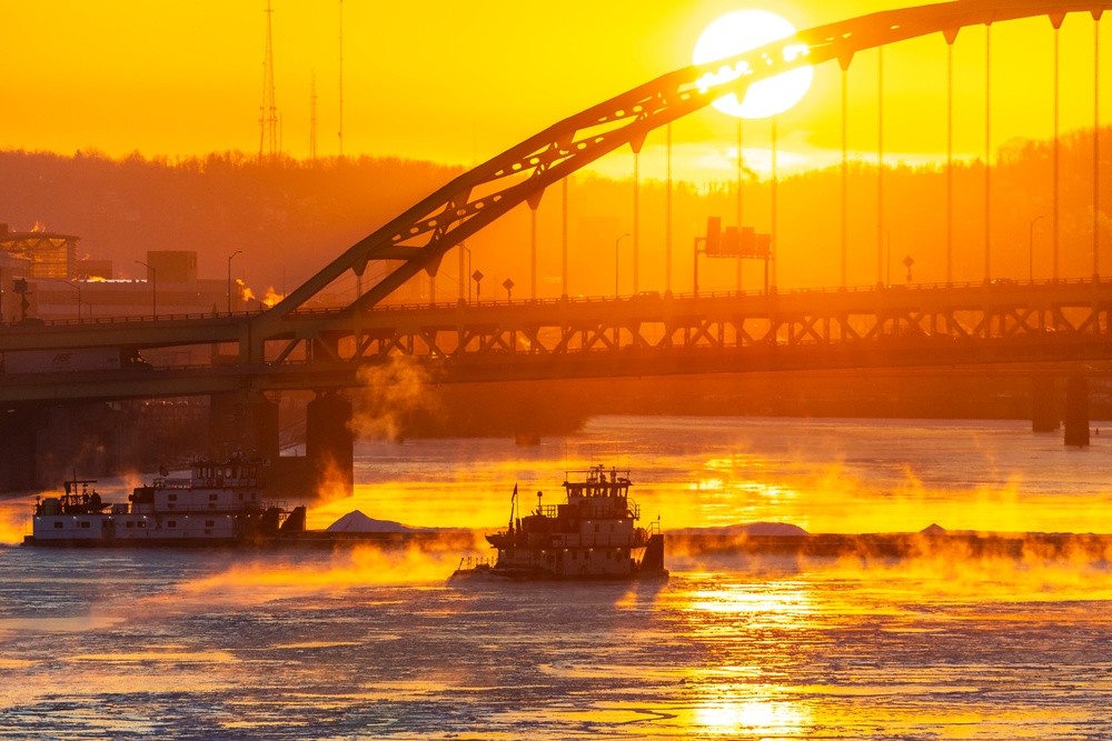 Sunfire and Ice: Towboats navigate through frozen rivers during Pittsburgh sunrise