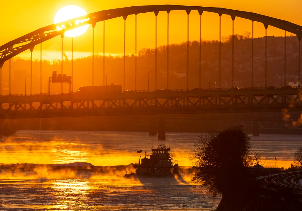 Sunfire and Ice: Towboats navigate through frozen rivers during Pittsburgh sunrise