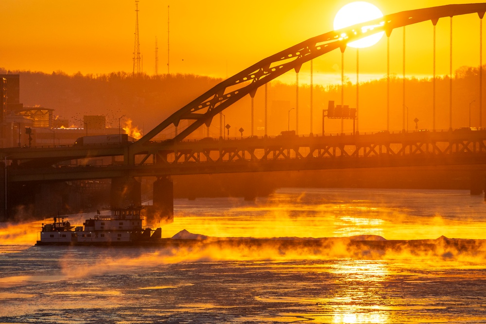 Sunfire and Ice: Towboats navigate through frozen rivers during Pittsburgh sunrise