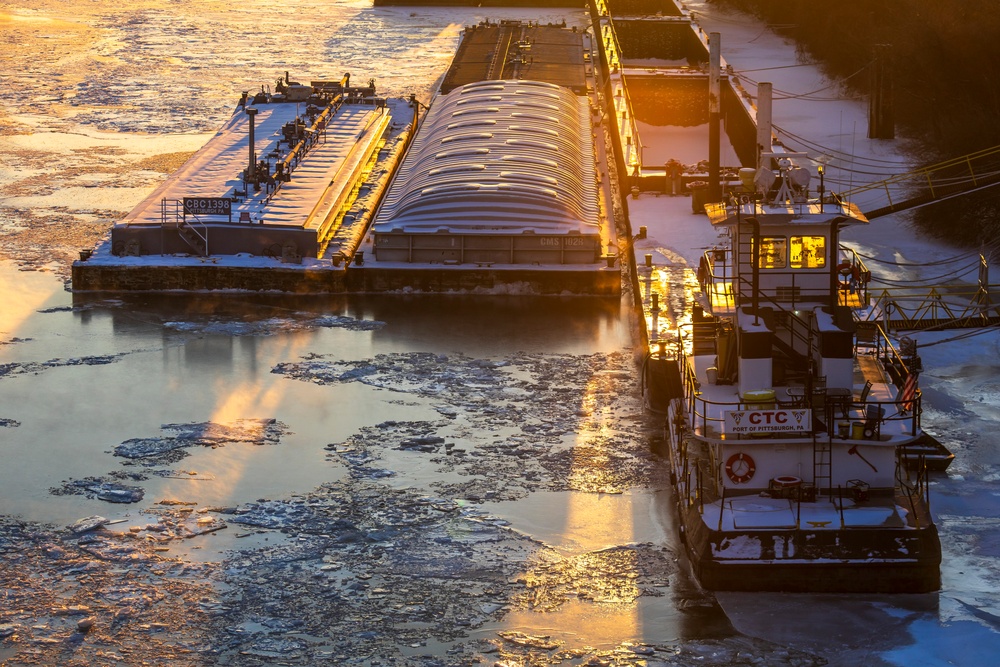 Sunfire and Ice: Towboats navigate through frozen rivers during Pittsburgh sunrise