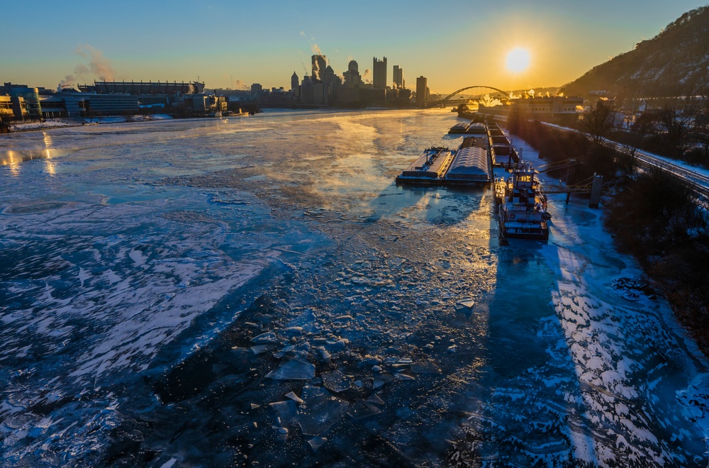 Sunfire and Ice: Towboats navigate through frozen rivers during Pittsburgh sunrise