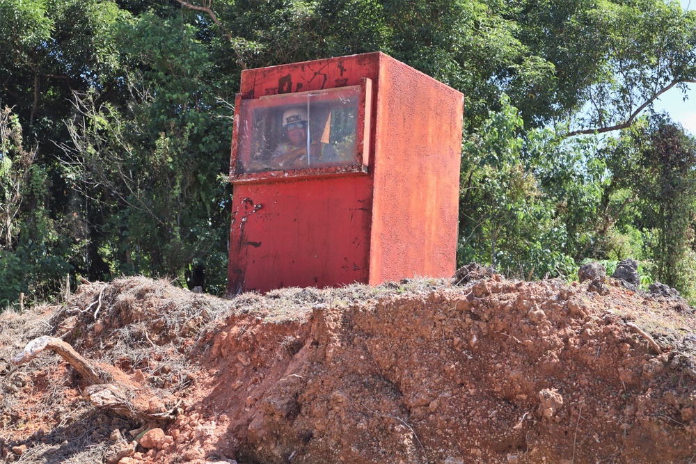 A Contractor Waves from Within a Blast Box Used for UXO Removal During Construction of Camp Blaz