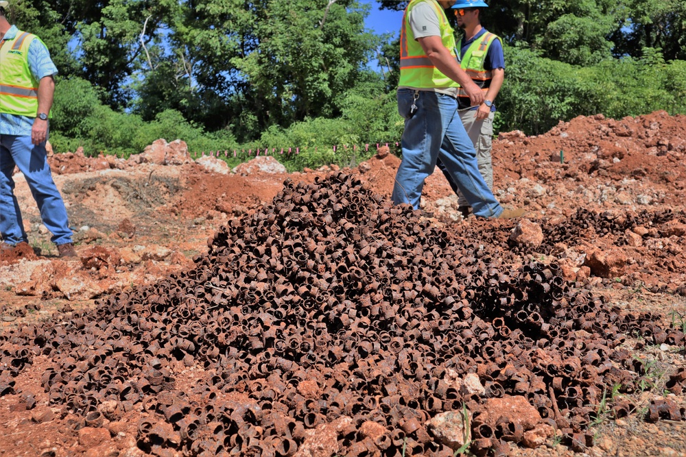 NAVFAC Staff Walk by a Pile of Scrap Metal Unearthed During Construction of Marine Corps Base Camp Blaz