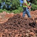 NAVFAC Staff Walk by a Pile of Scrap Metal Unearthed During Construction of Marine Corps Base Camp Blaz