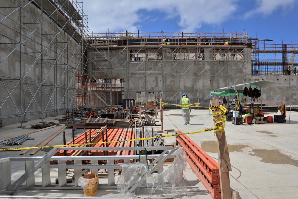 A Contractor Walks by Piles of Scaffolding and Construction Materials on a Construction Site at Marine Corps Base Camp Blaz