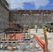 A Contractor Walks by Piles of Scaffolding and Construction Materials on a Construction Site at Marine Corps Base Camp Blaz