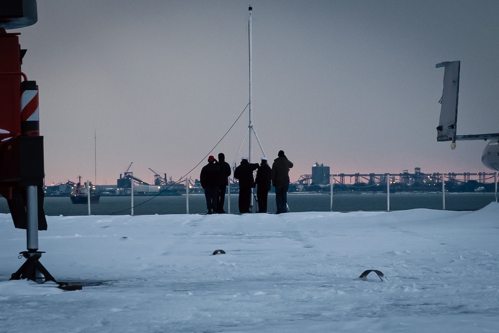 USS Gerald R. Ford (CVN 78) Sailors observe colors during a winter storm