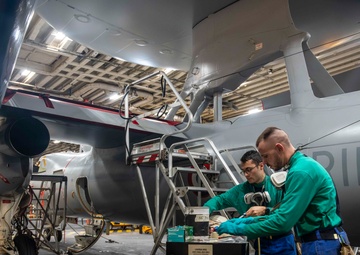 French sailors perform maintenance on an E-2C Hawkeye aboard FS Charles De Gaulle