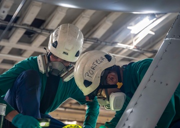 French sailors perform maintenance on an E-2C Hawkeye aboard FS Charles De Gaulle