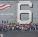 Sailors assigned to the USS America (LHA 6) and their families pose for a photo during a tiger cruise.