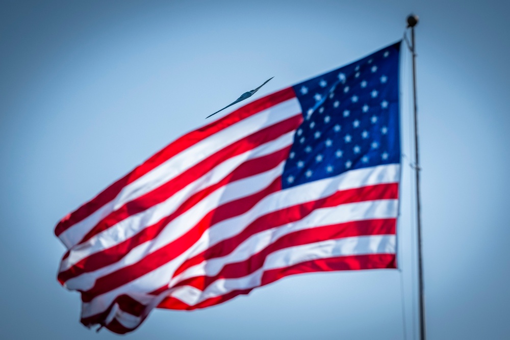 B-2A Spirit stealth bomber flyover above American flag during U.S. Air Force Basic Military Training graduation