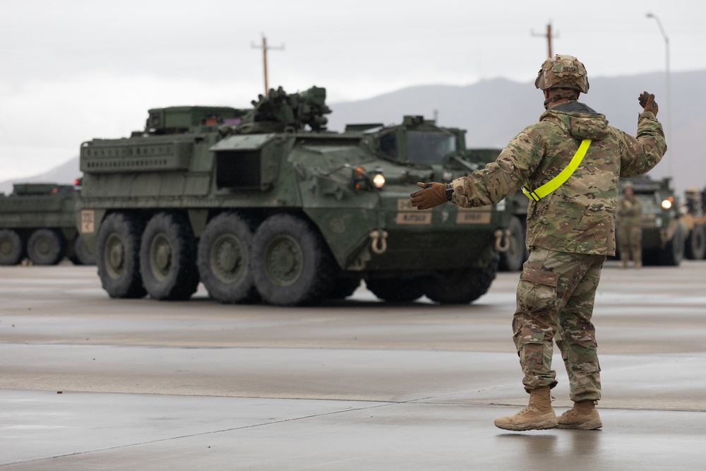U.S. Soldiers move and ground guide Stryker combat vehicles to a motorpool