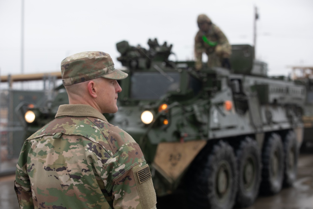 U.S. Soldiers move and ground guide Stryker combat vehicles to a motorpool