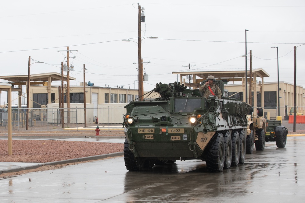 U.S. Soldiers move and ground guide Stryker combat vehicles to a motorpool