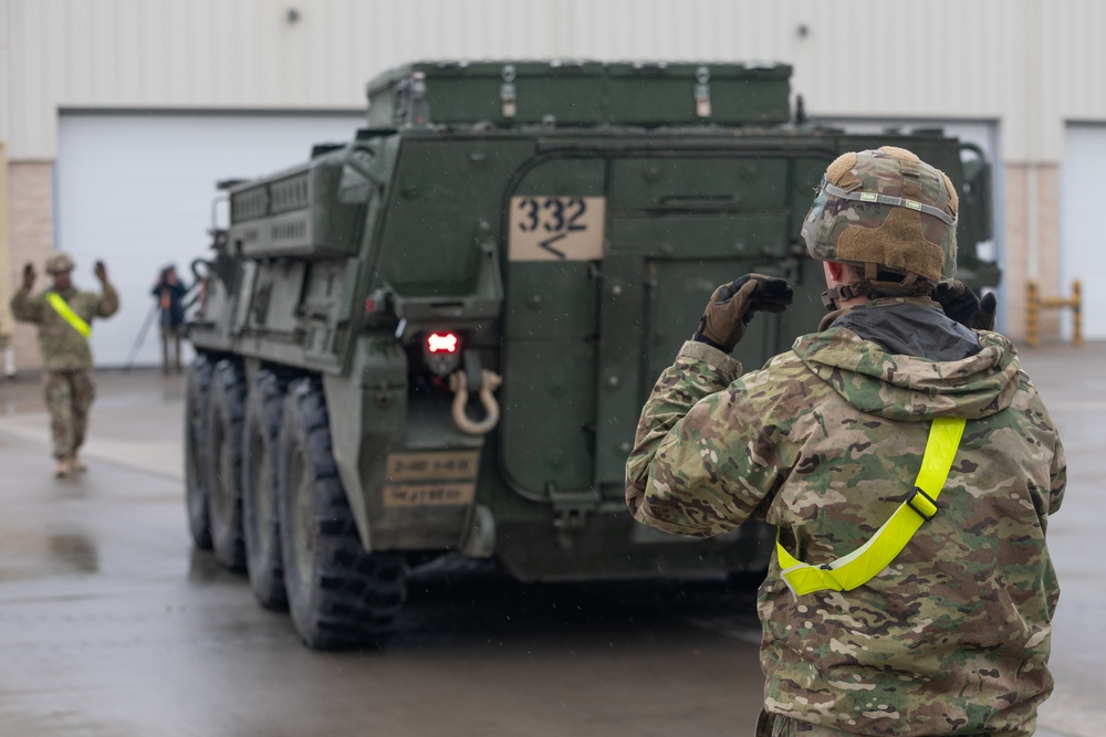 U.S. Soldiers move and ground guide Stryker combat vehicles to a motorpool