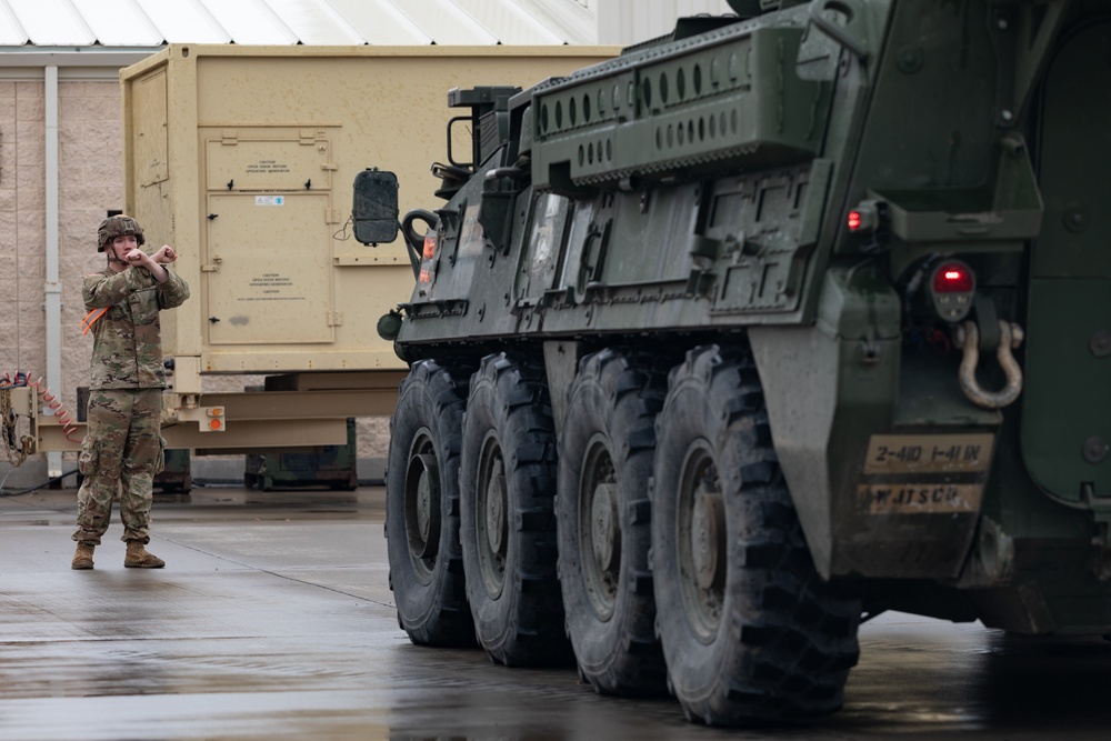 U.S. Soldiers move and ground guide Stryker combat vehicles to a motorpool