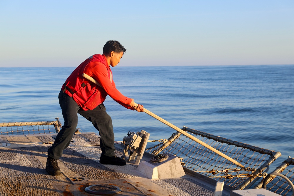 U.S. Navy Sailor releases the side nets prior to flight operations on board the USS Bulkeley.