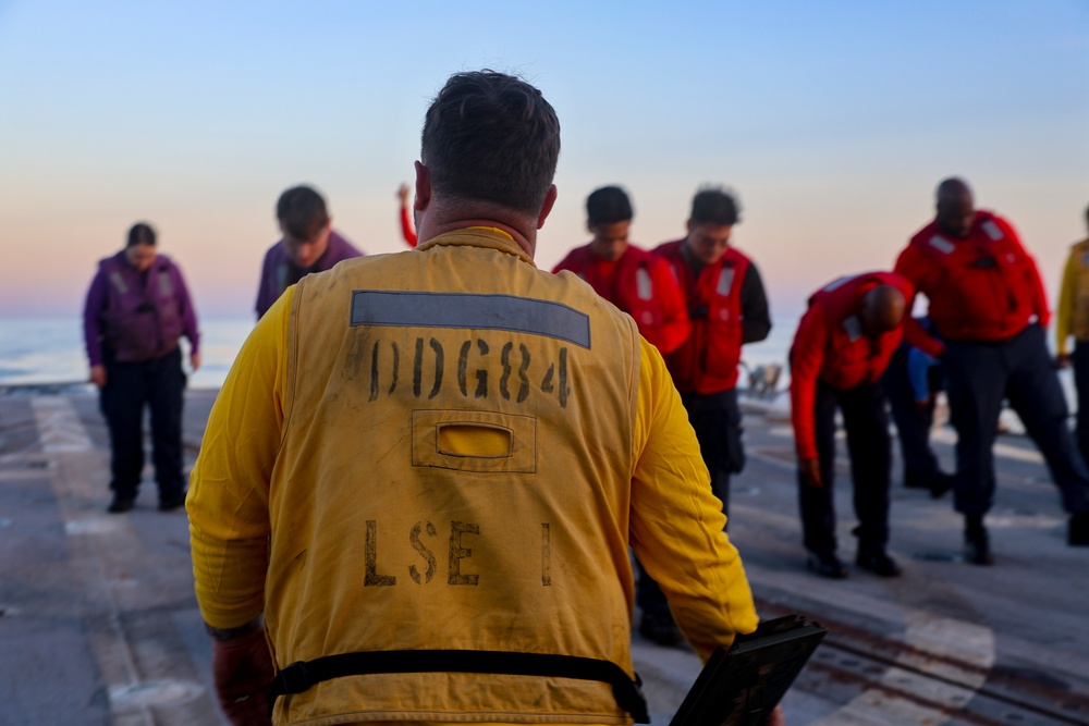 U.S. Navy Sailors conduct a Foreign Object Debris (FOD) check on the flight deck of the USS Bulkeley.