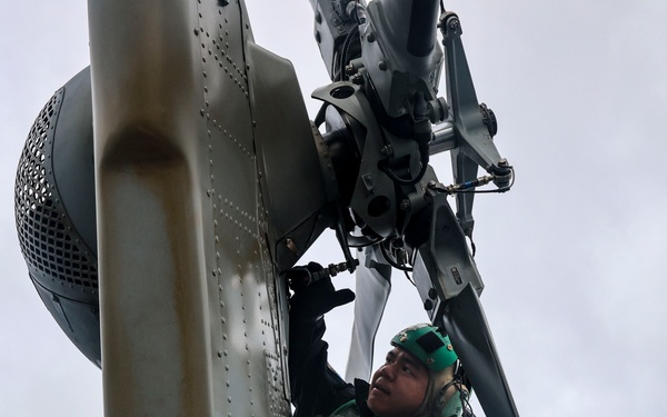 Ground crew perform maintenance on a MH-60R Sea Hawk helicopter.