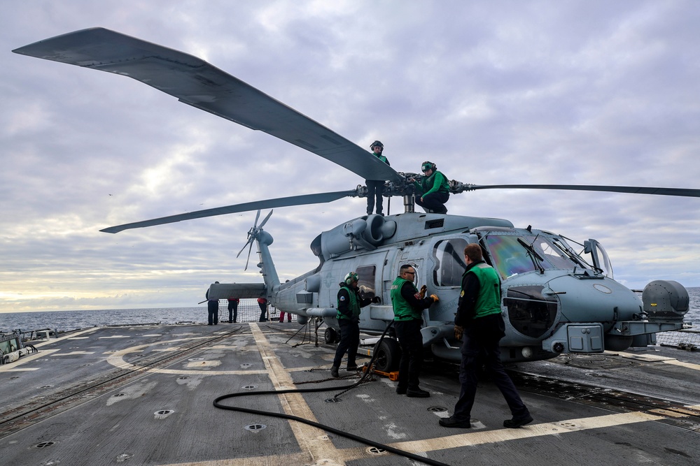 Ground crew conduct pre-flight checks on a MH-60R Sea Hawk helicopter.