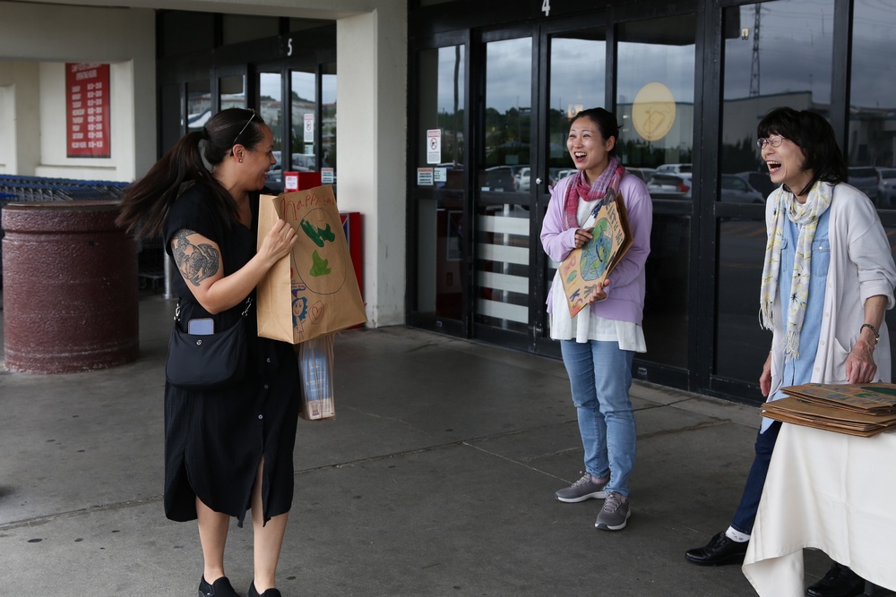 Environmental Affairs Branch members pass out paper bags designed by students from Killin Elementary