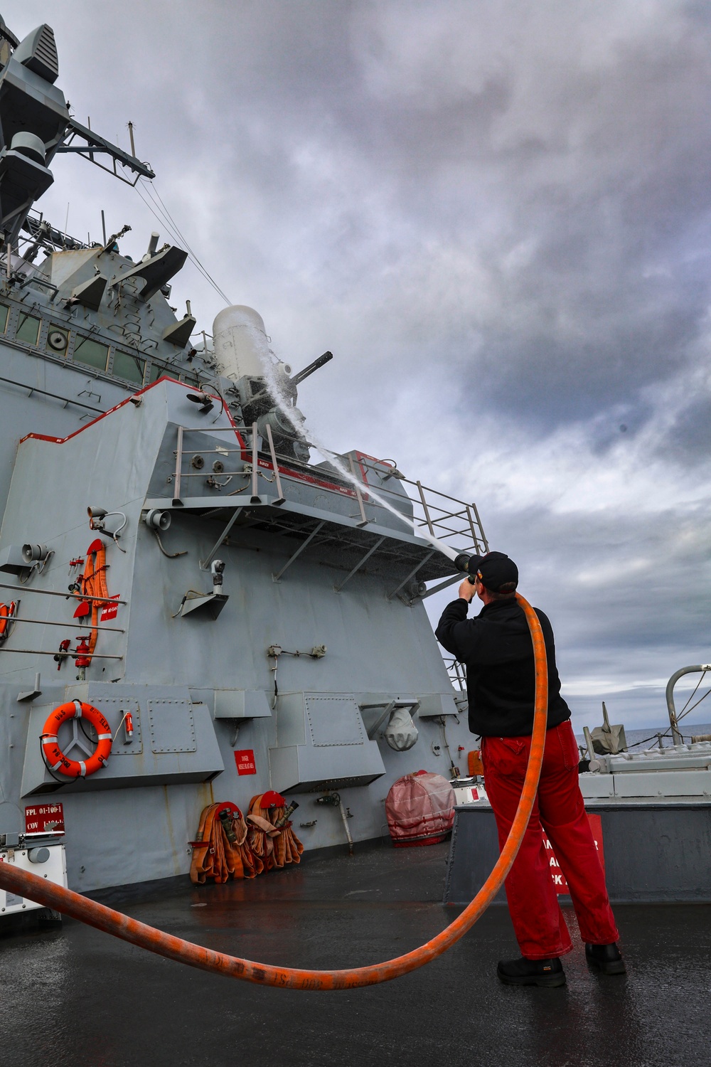 U.S. Navy Sailor conducts a fresh-water washdown aboard the USS Bulkeley