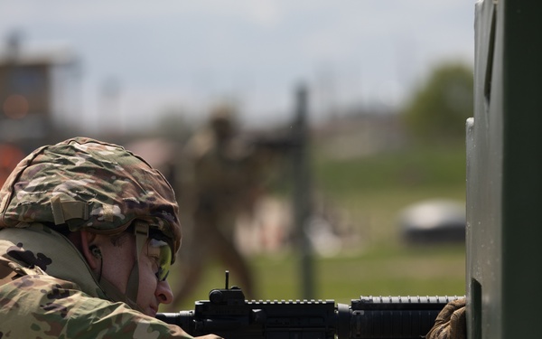 U.S. Army Sgt. Derek Combs, 350th Public Affairs Detachment, aims his M4